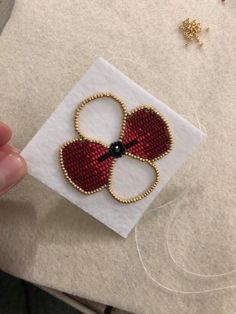 someone is holding up a piece of beaded fabric to make a flower brooch