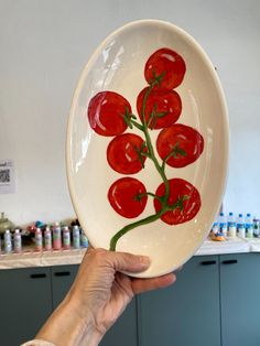 a person holding up a plate with red peppers painted on the front and side of it