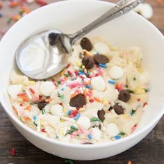 a bowl filled with cereal and sprinkles on top of a wooden table