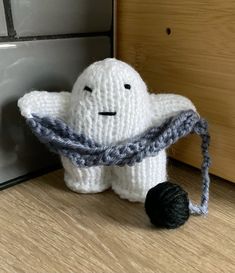 a knitted ghost with a ball of yarn around it's neck sitting on the floor