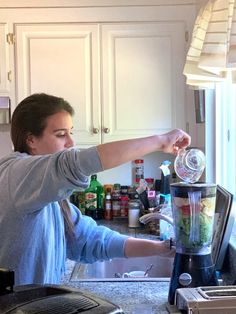 a woman pouring something into a blender in the kitchen