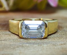 a yellow gold ring with an emerald cut diamond