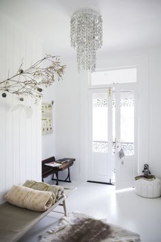 a white room with a chandelier hanging from the ceiling and a fur rug on the floor