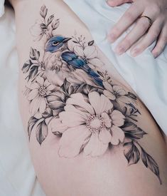 a woman's thigh with flowers and a bird on it