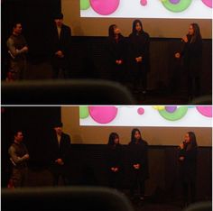 three people standing in front of a projector screen and one person holding a microphone