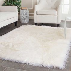 a living room with two white chairs and a rug