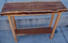 a wooden table sitting on top of a sidewalk next to a cement wall and building