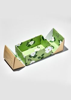 an open green box with white flowers on it and a card in the bottom right corner