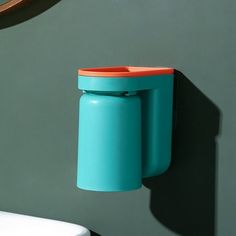 a wall mounted toothbrush holder in the shape of a cup hanging from a hook