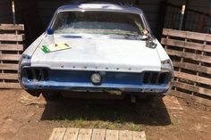 an old car is parked in front of some pallets