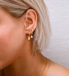 a woman with blonde hair wearing gold earrings