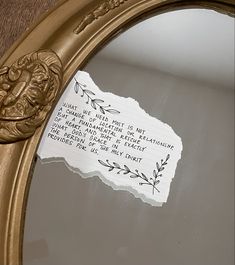 a piece of paper with writing on it sitting in front of a gold frame mirror