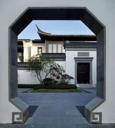 an entrance to a white building with a tree in the middle