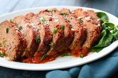 meatloaf with sauce and spinach leaves on a white plate, ready to be eaten