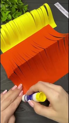 someone is painting an orange and yellow piece of paper