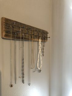 a wooden shelf with several necklaces hanging from it's sides and two hooks on the wall