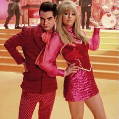 a man and woman dressed in red posing for the camera with their hands on their hips