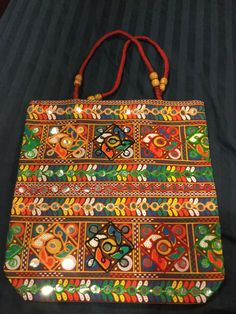 Handmade tote. Very colorful and attractive. Handles have beads. Embroidered with plastic mirrors. Not all mirrors in middle. Plain black on the flip side. Size 15 x 15.5  1 black 2 red 1 green Festive Rectangular Bag With Mirror Work, Handheld Multicolor Bags With Handwork, Festive Rectangular Shoulder Bag With Mirror Work, Beaded Bags For Everyday Use And Festivals, Everyday Beaded Bags For Festivals, Festival Bag With Mirror Work, Rectangular Shape, Beaded Multicolor Embroidered Rectangular Shoulder Bag, Festival Rectangular Bag With Mirror Work, Multicolor Embroidered Beaded Rectangular Shoulder Bag