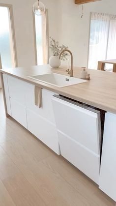 a kitchen with white cabinets and an island in the middle is seen from across the room