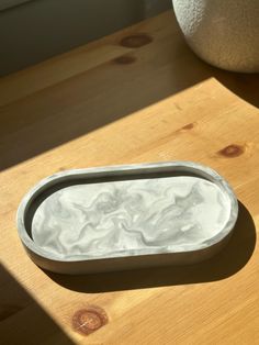 a bowl sitting on top of a wooden table next to a white ball and vase