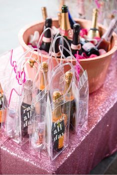 several bottles of champagne are sitting in clear bags on a pink tableclothed cloth