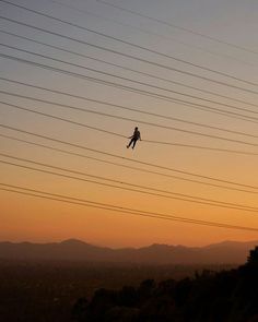 a person flying through the air while riding skis on top of a hill at sunset