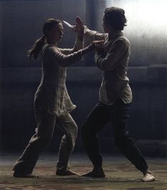 two people are dancing in the dark with one holding his hand up to the other