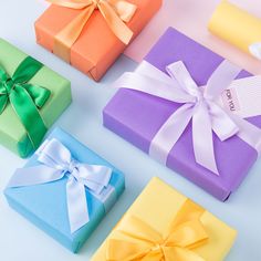 four different colored gift boxes with ribbons on them