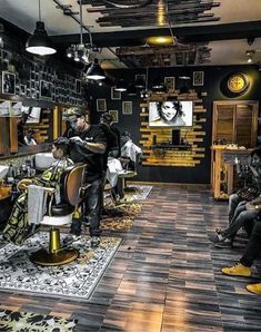 a man getting his hair cut in a barbershop with other people sitting and standing around