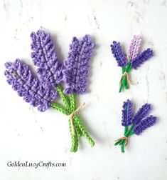 three crocheted lavender flowers on a white surface