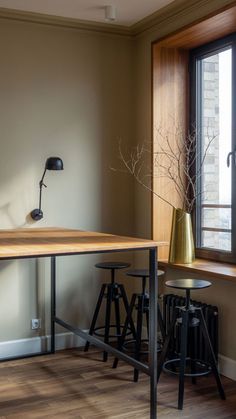 an empty room with two stools and a table in front of a large window