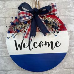 a welcome sign hanging on the side of a brick wall with blue and white ribbon