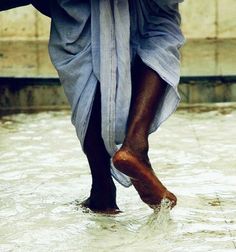 a person walking in the water with an umbrella over their head and shoes on his feet