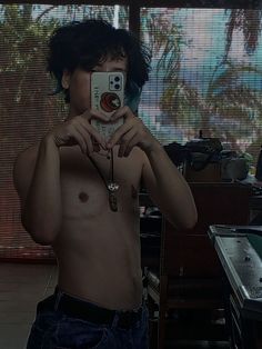 a shirtless man taking a selfie with his cell phone in front of him