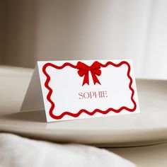 a place card with a red bow on it