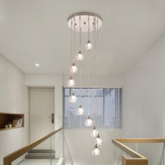 a room with some lights hanging from it's ceiling and stairs leading up to the second floor