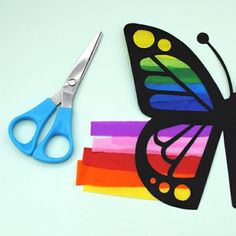 a paper butterfly cut out with scissors on top of strips of rainbow colored tissue paper