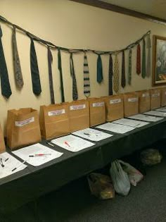 there is a long table with ties hanging on the wall and bags lined up in front of it