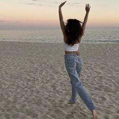 a woman jumping up in the air on a beach