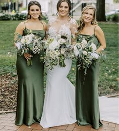 three bridesmaids pose for a photo in their green gowns and bouquets