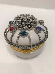 a white box with many different colored stones on it's lid, sitting on a table