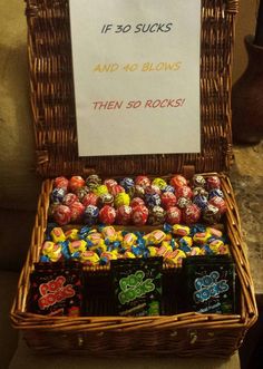 a wicker basket filled with lots of chocolate candies next to a sign that says if 30 sucks and 40 blows then 50 rocks