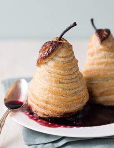 two pieces of pastry sitting on top of a plate next to a spoon and fork