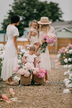 three women and two girls in white dresses with pink flowers on the ground at a flower farm