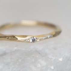 a yellow gold ring with a single diamond on top of some white rocks and snow