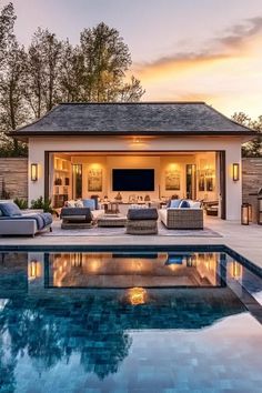 an outdoor living area with couches and a television next to a swimming pool at sunset