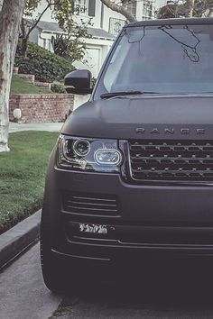 a black range rover is parked on the side of the road in front of a house