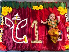 a baby laying on top of a red cloth covered in flowers and leaves next to a sign that says i love you