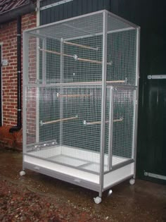 a white bird cage sitting on top of a wooden floor next to a brick building