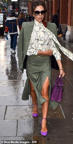 a woman is walking down the street with an umbrella over her head and purple handbag